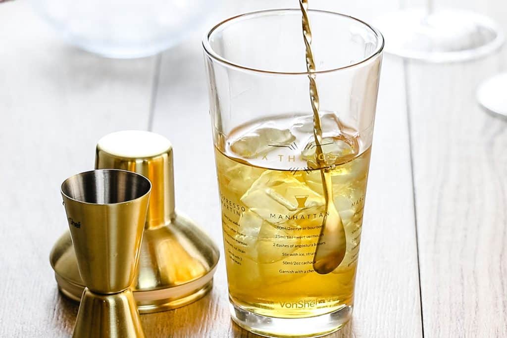 manhattan cocktail being stirred in a cocktail shaker.