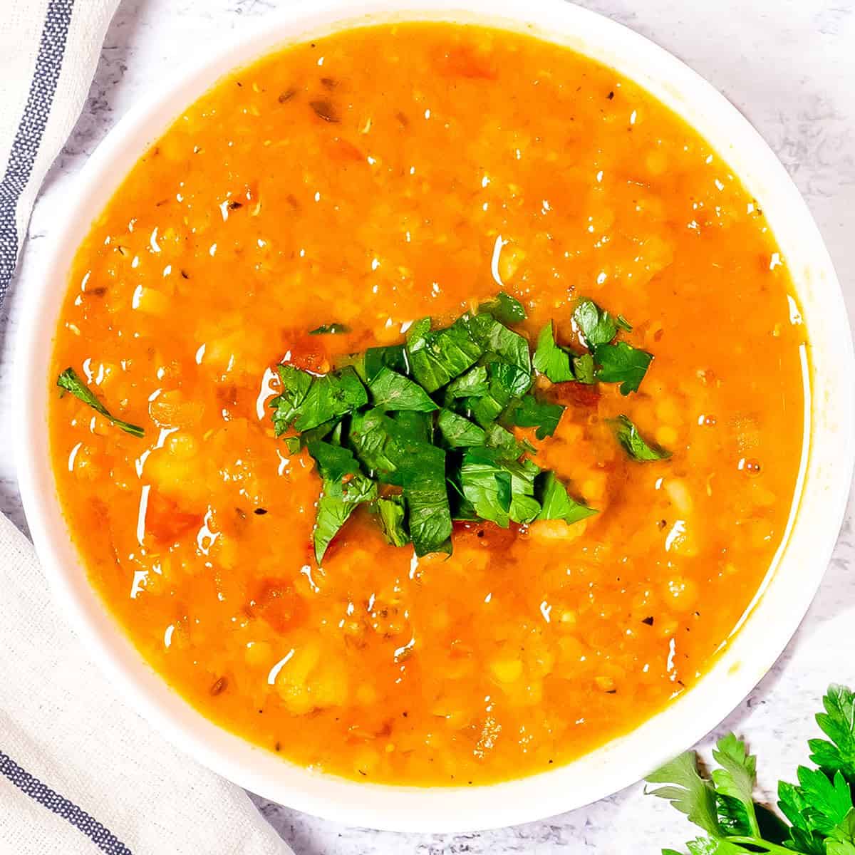 a bowl of red lentil soup with chopped cilantro on top