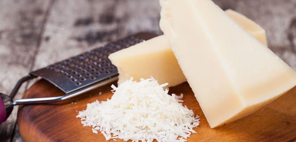 grated parmesan cheese and metal grater on wooden board