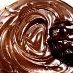 An overhead shot of chocolate mixed into peanut butter with a whisk making a swirl