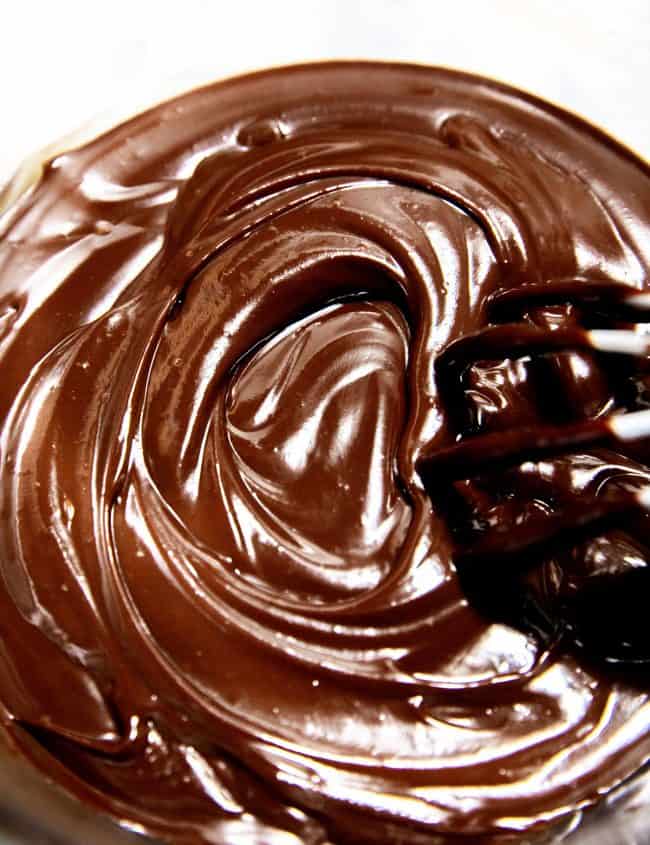An overhead shot of chocolate mixed into peanut butter with a whisk making a swirl