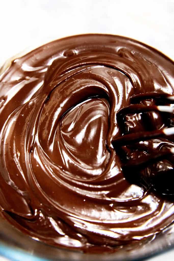 An overhead shot of chocolate ganache with a whisk making a swirl