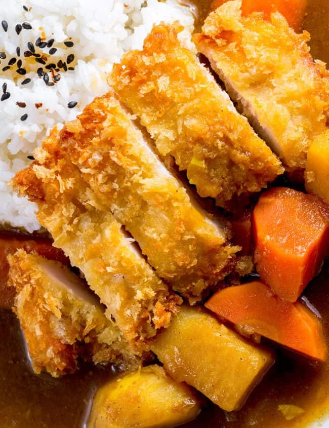 a breaded chicken cutlet served with rice and curry