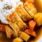 a breaded chicken cutlet served with rice and curry