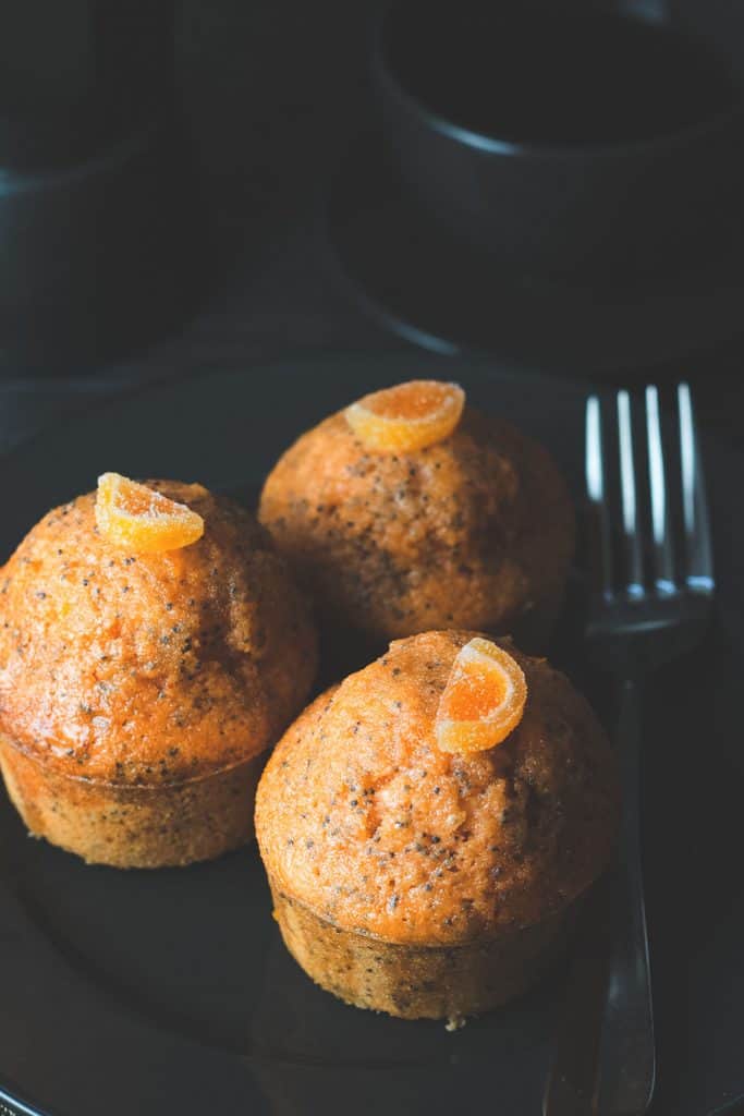 three orange poppy seed cakes ready to eat with a fork beside.
