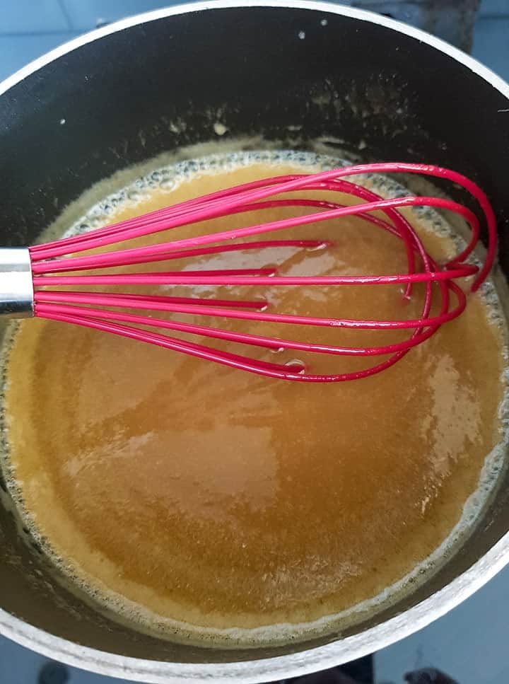 sugar and butter being whisked in a pan to make caramel.