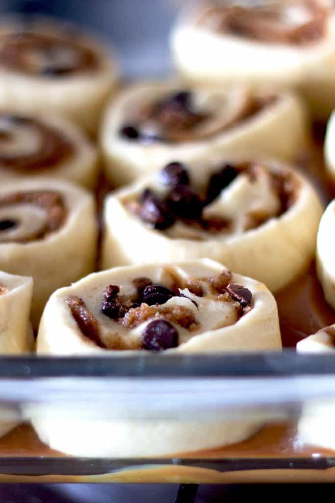 sticky buns lined up in a pan on top of some caramel, ready to be baked.