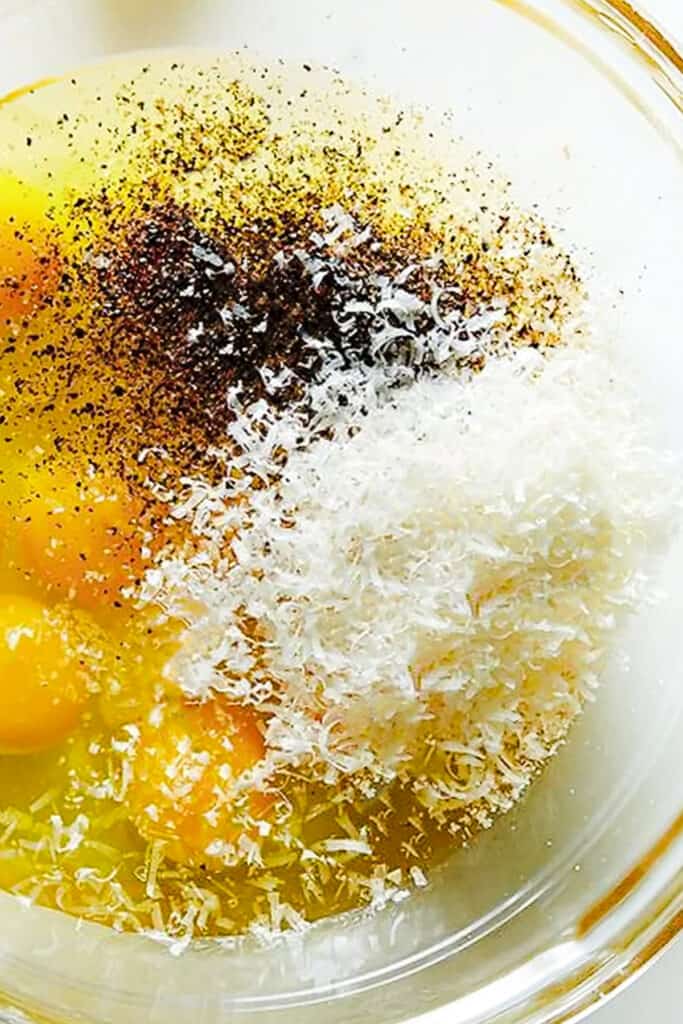 cheese, freshly grated black pepper and eggs in a bowl