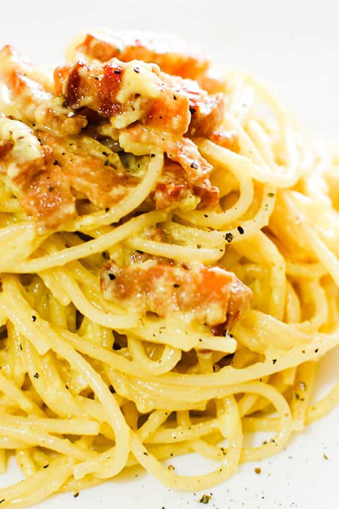 Spaghetti Alla Carbonara piled high on a plate with crisp guanciale