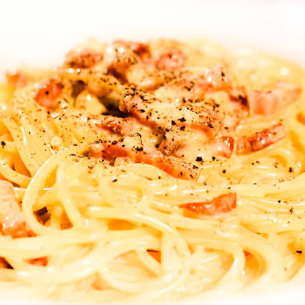 a close up image of Spaghetti Alla Carbonara with a white background