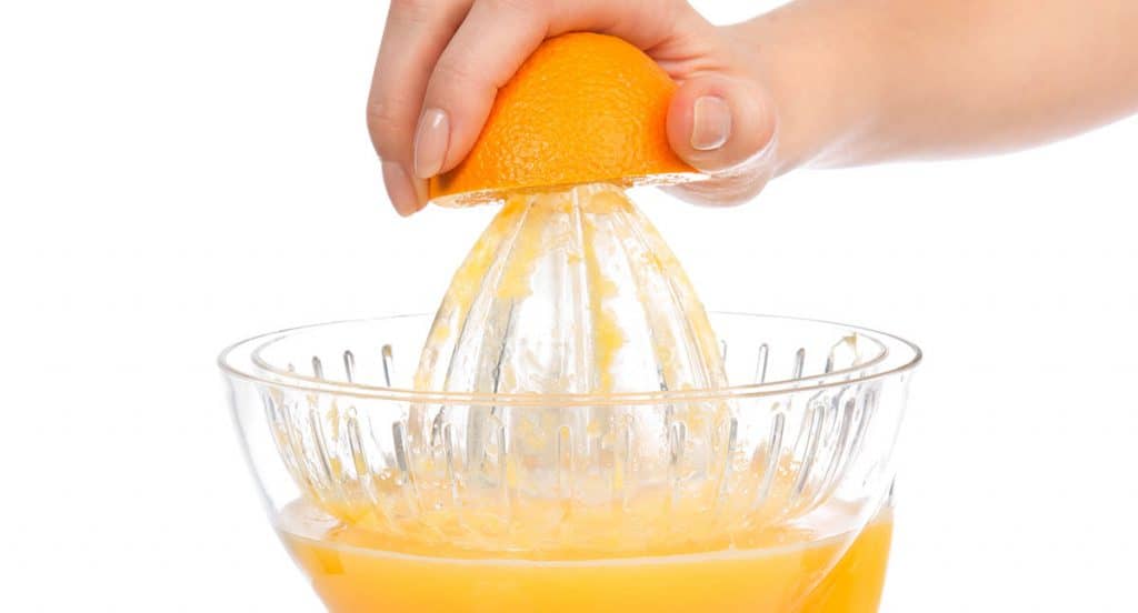 Preparing fresh orange juice squeezed with electric juicer