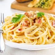 Spaghetti Alla Carbonara on a plate with garlic bread in the background