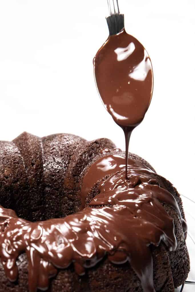 chocolate glaze being applied to a chocolate cake