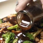 stir fry sauce being poured onto chicken and broccoli