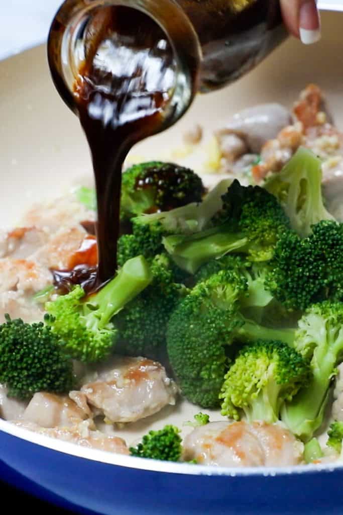 stir fry sauce being poured onto chicken and broccoli