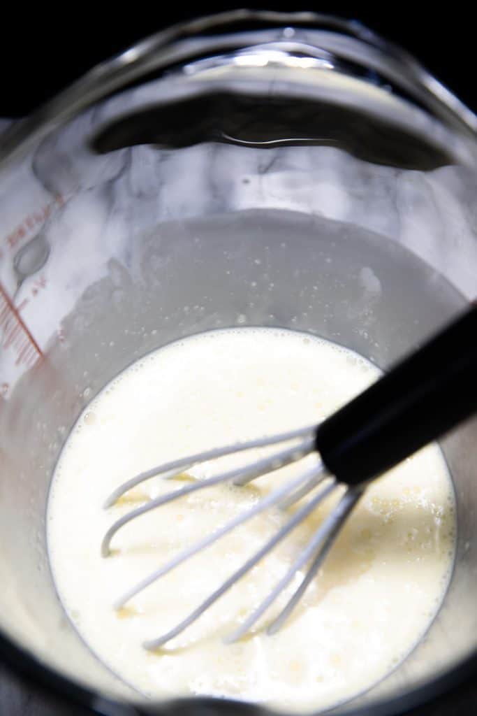 heavy cream in a pitcher with a whisk