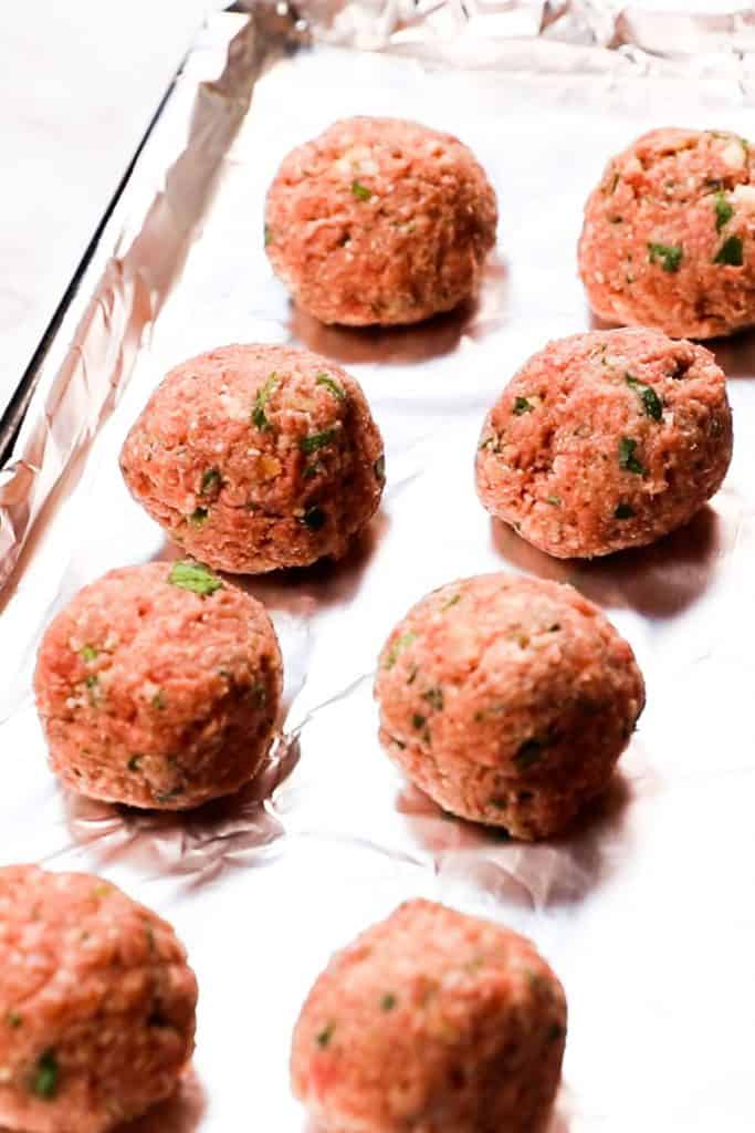 uncooked meatballs on a baking tray