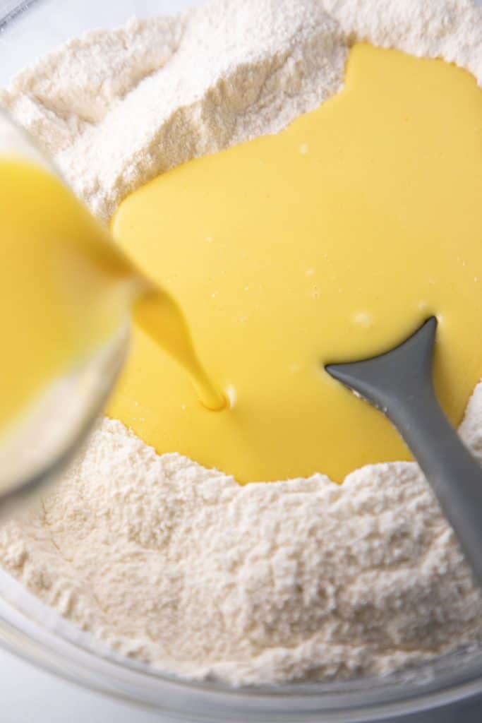 wet ingredients being poured into a well of dry ingerdients