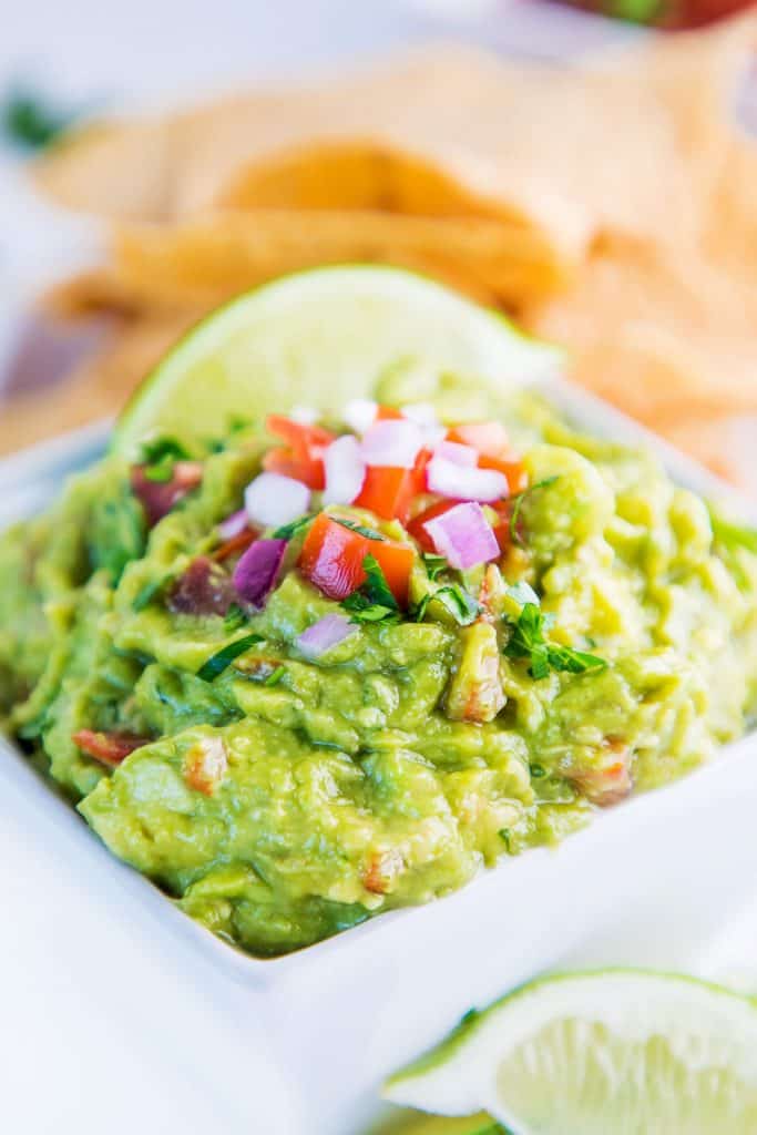 a bowl of guacamole with sliced lime on top