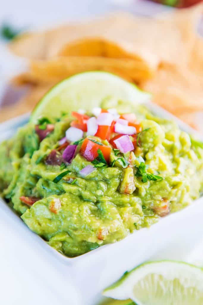 a bowl of guacamole with sliced lime on top