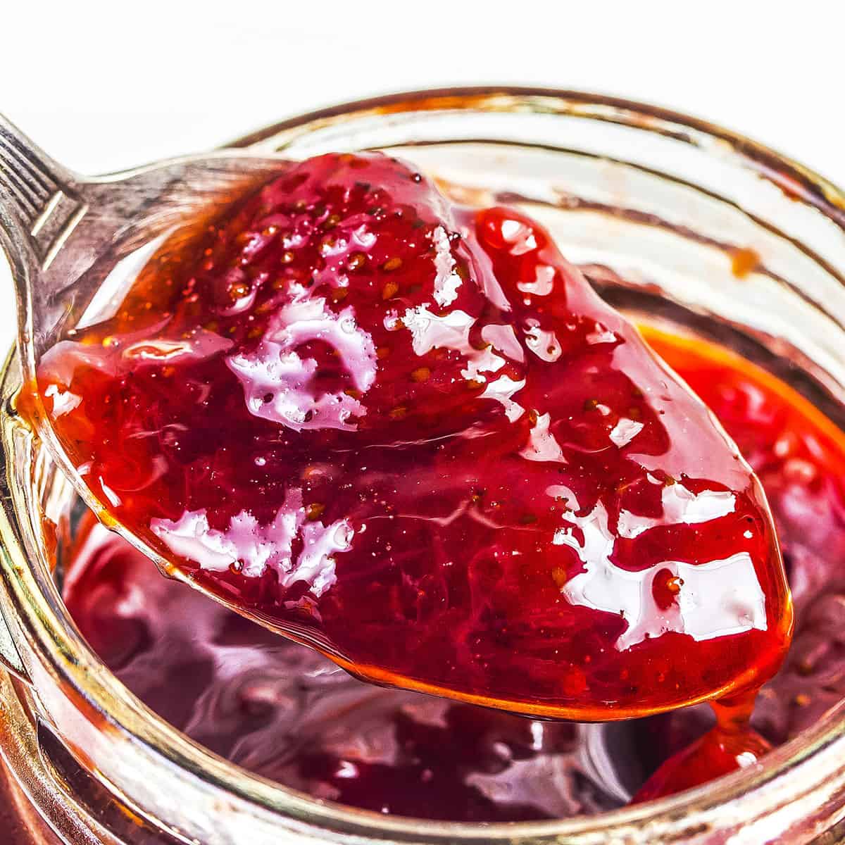 Strawberry jam being spooned out of a jar