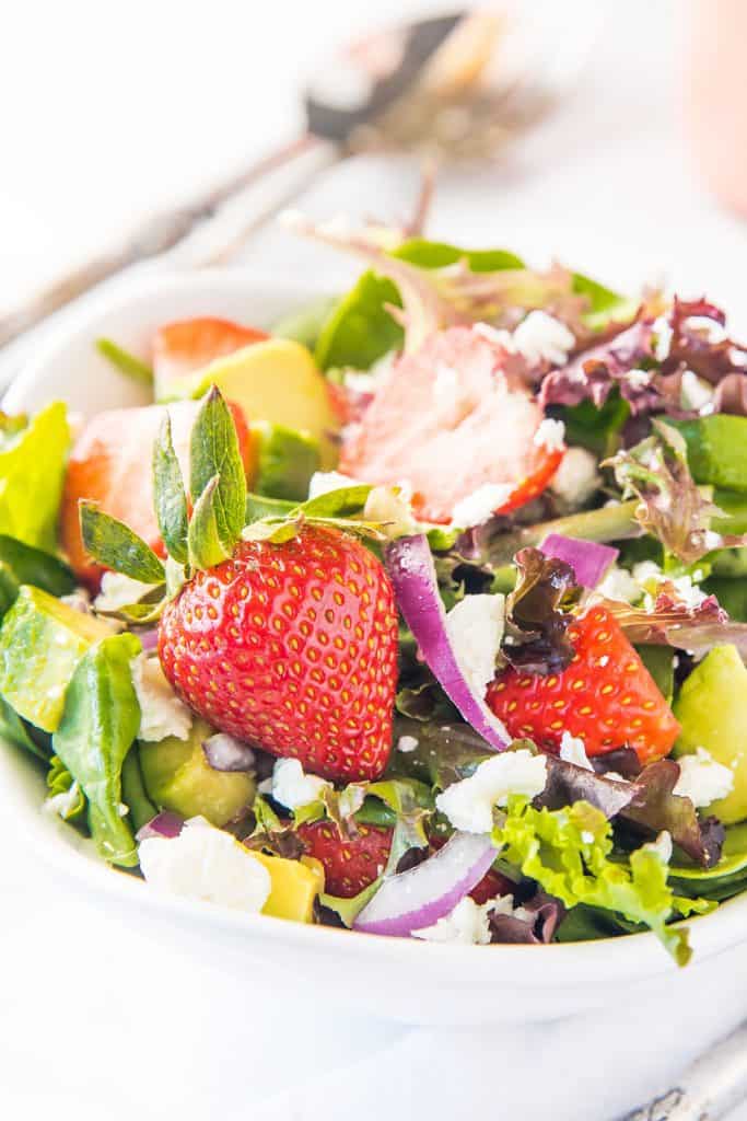 a bowl of salad with strawberries