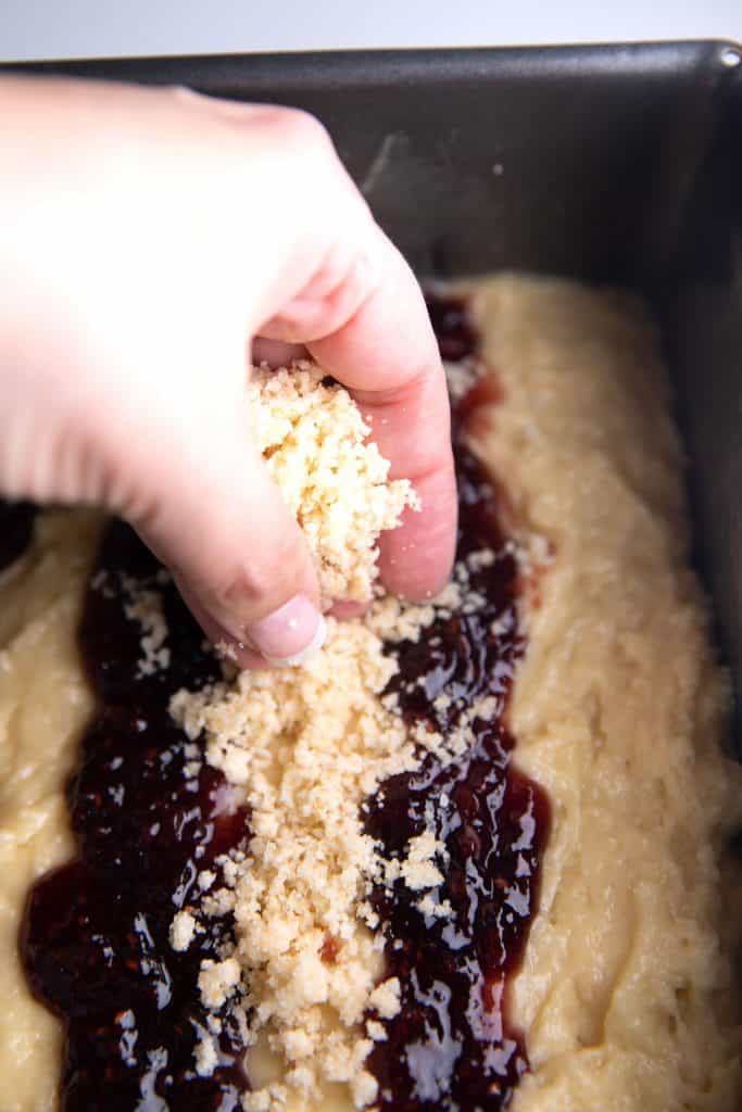 crumble topping being crumbled on top of the cake