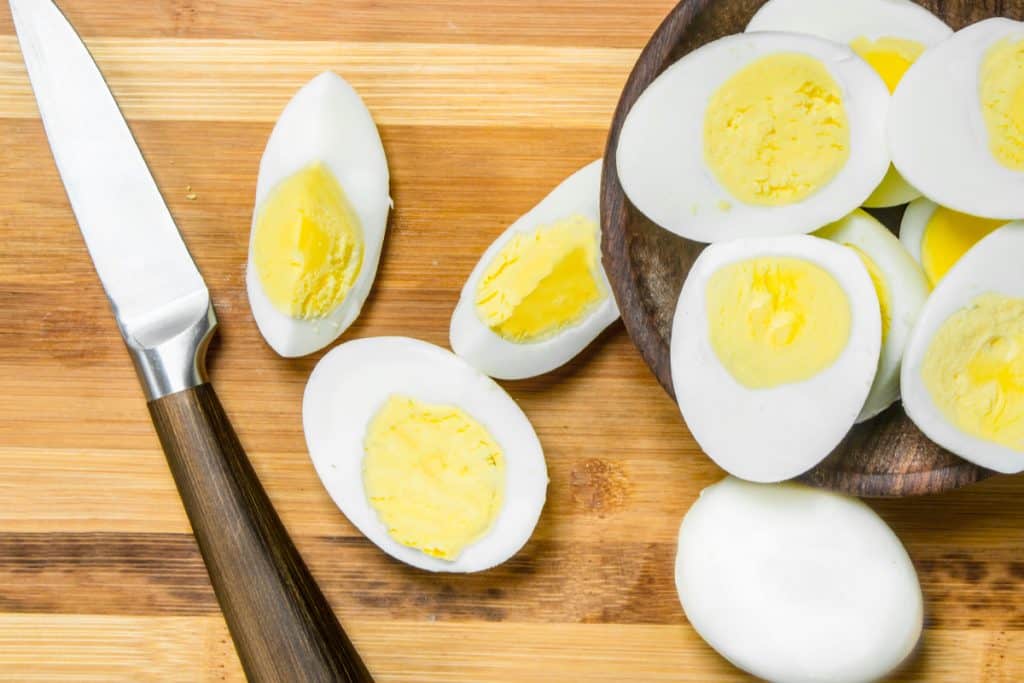 Sliced boiled eggs on cutting board. On a wooden background.