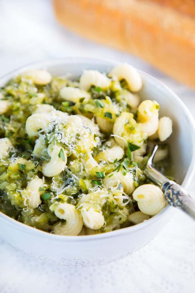 a bowl of pasta and zucchini with a spoon in it