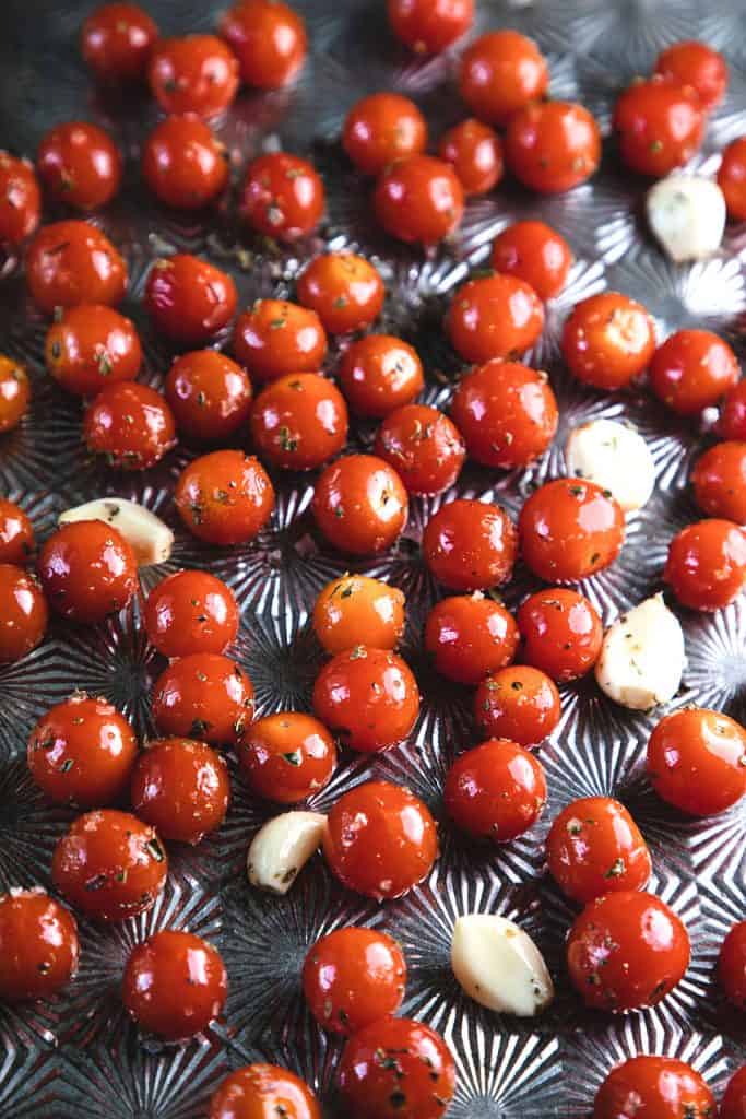 tomatoes on an oven tray with garlic and herbs