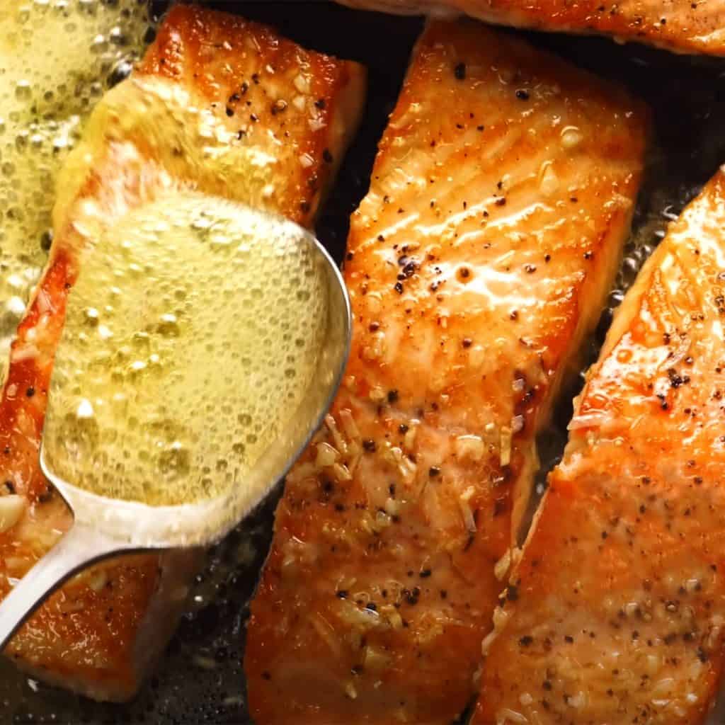 salmon filets being basted with butter