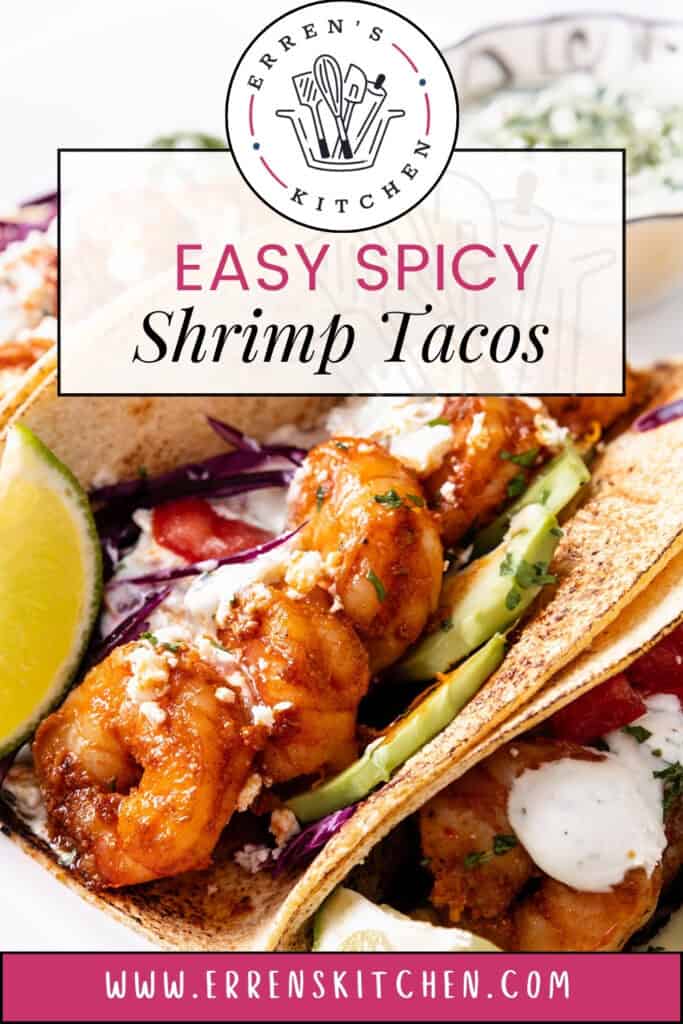 A close-up photo of two shrimp tacos on a white plate. The tacos are filled with plump shrimp, sliced avocado, and a white crema sauce. Text overlay on the plate reads "Erren's Kitchen Easy Spicy Shrimp Tacos".