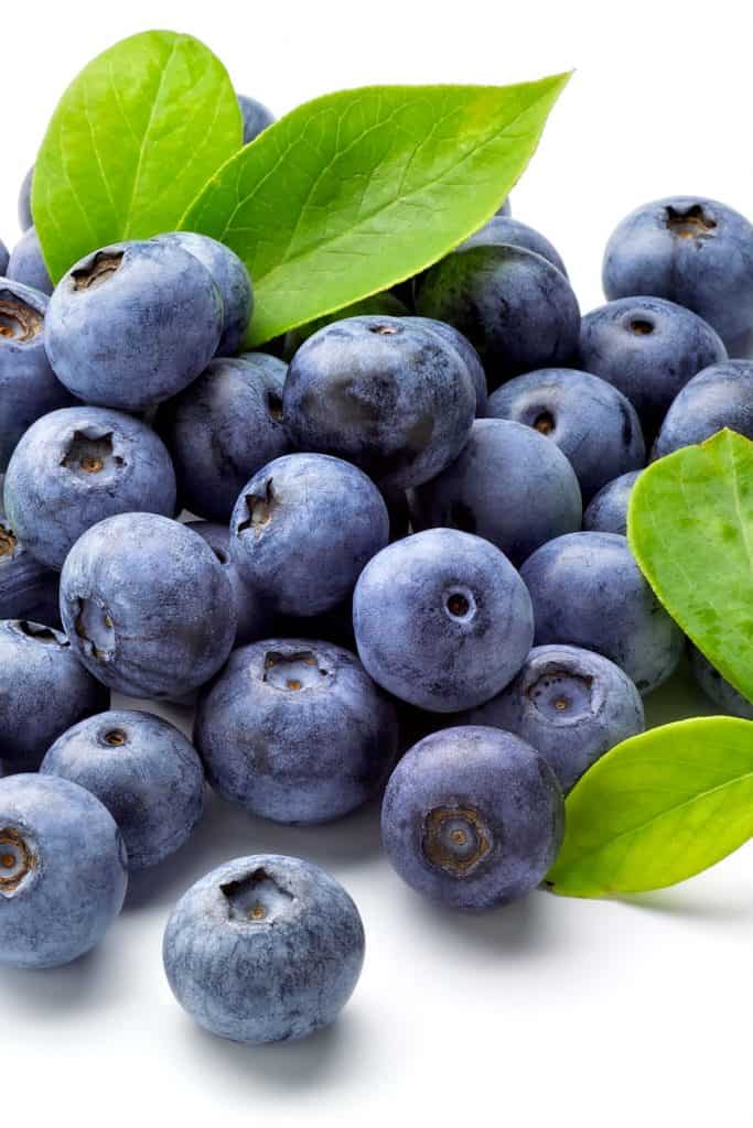 a plie of fresh blueberries with some leaves
