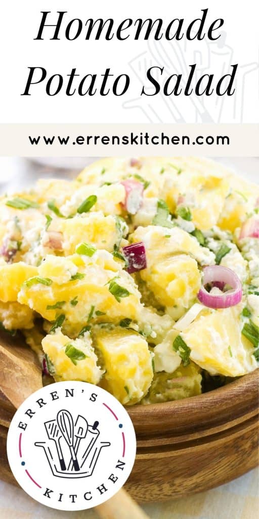 potato salad in a wooden bowl with a wooden spoon next to it and salt and pepper in the background