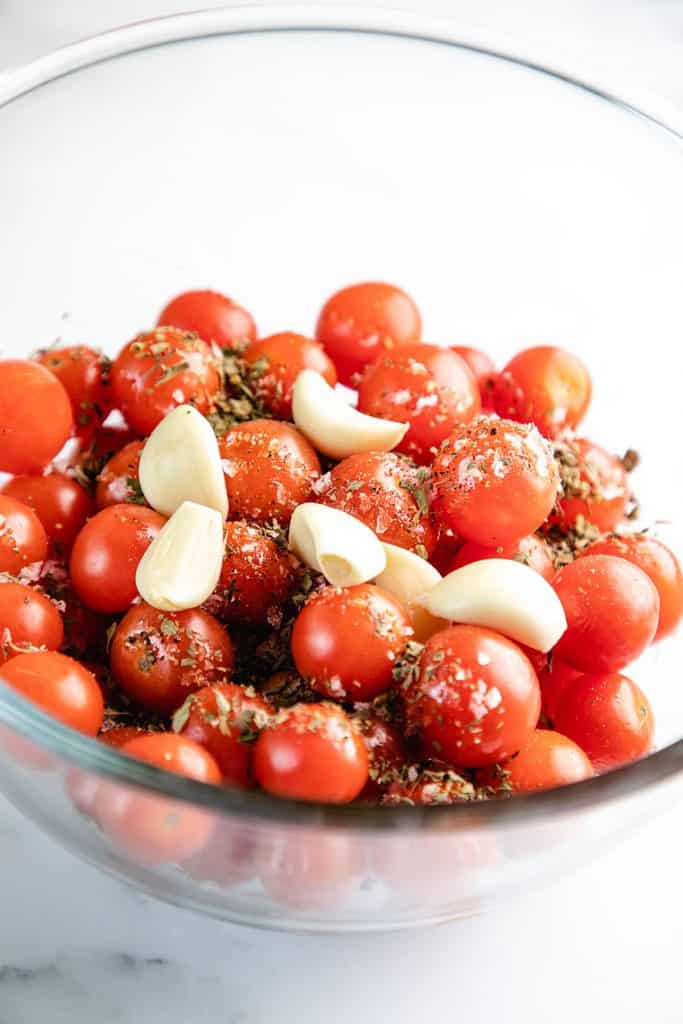 a bowl of cherry tomatoes with garlic cloves