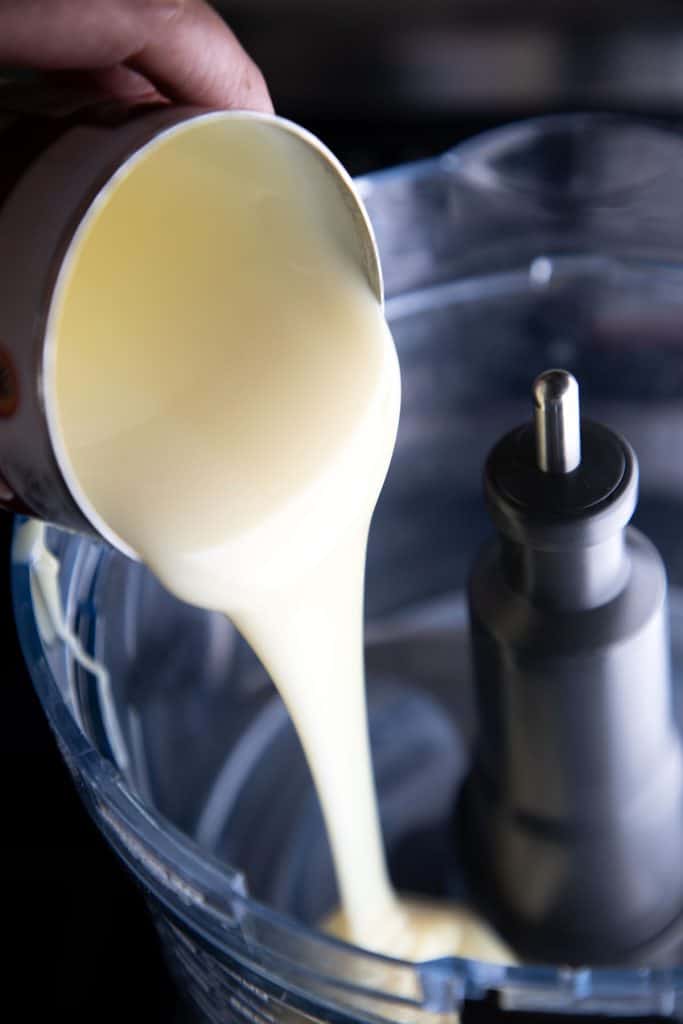 condensed milk being poured into a mixer