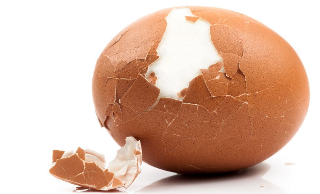 peeled boiled egg on white background
