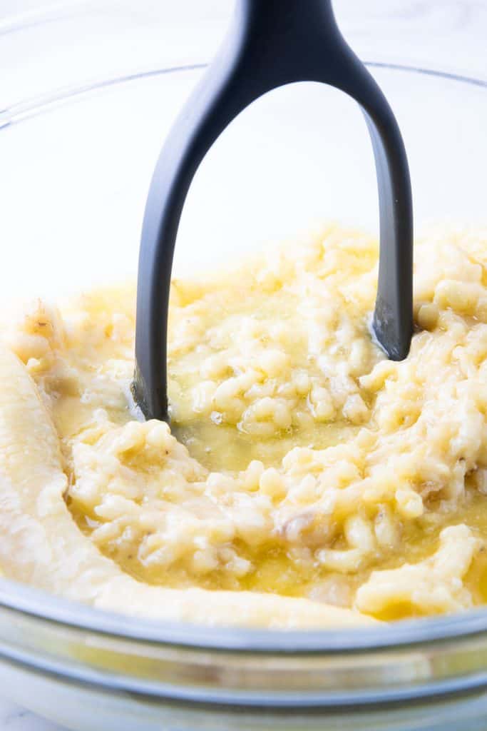 bananas being mashed with a potato masher