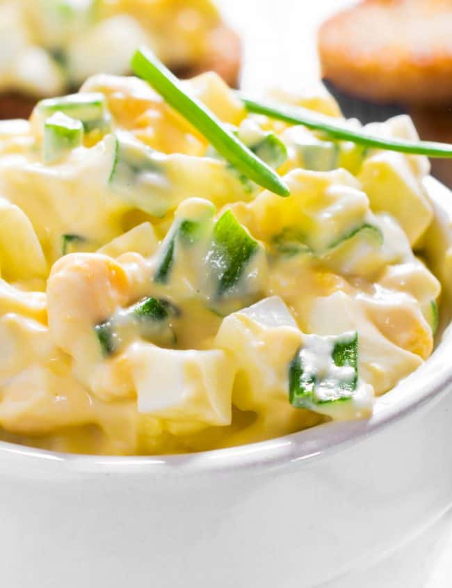 a close up of egg salad in a white bowl