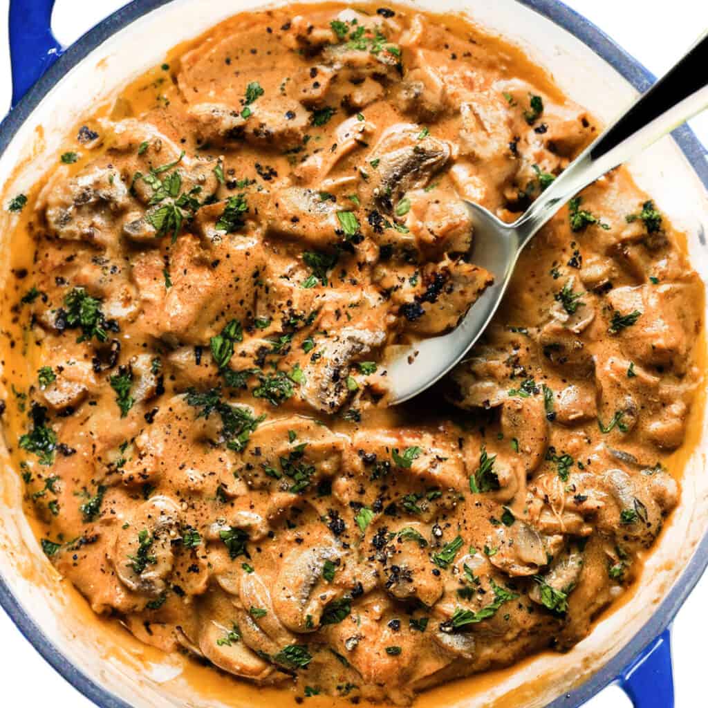 the finished Chicken Stroganoff with a serving spoon in the pan.