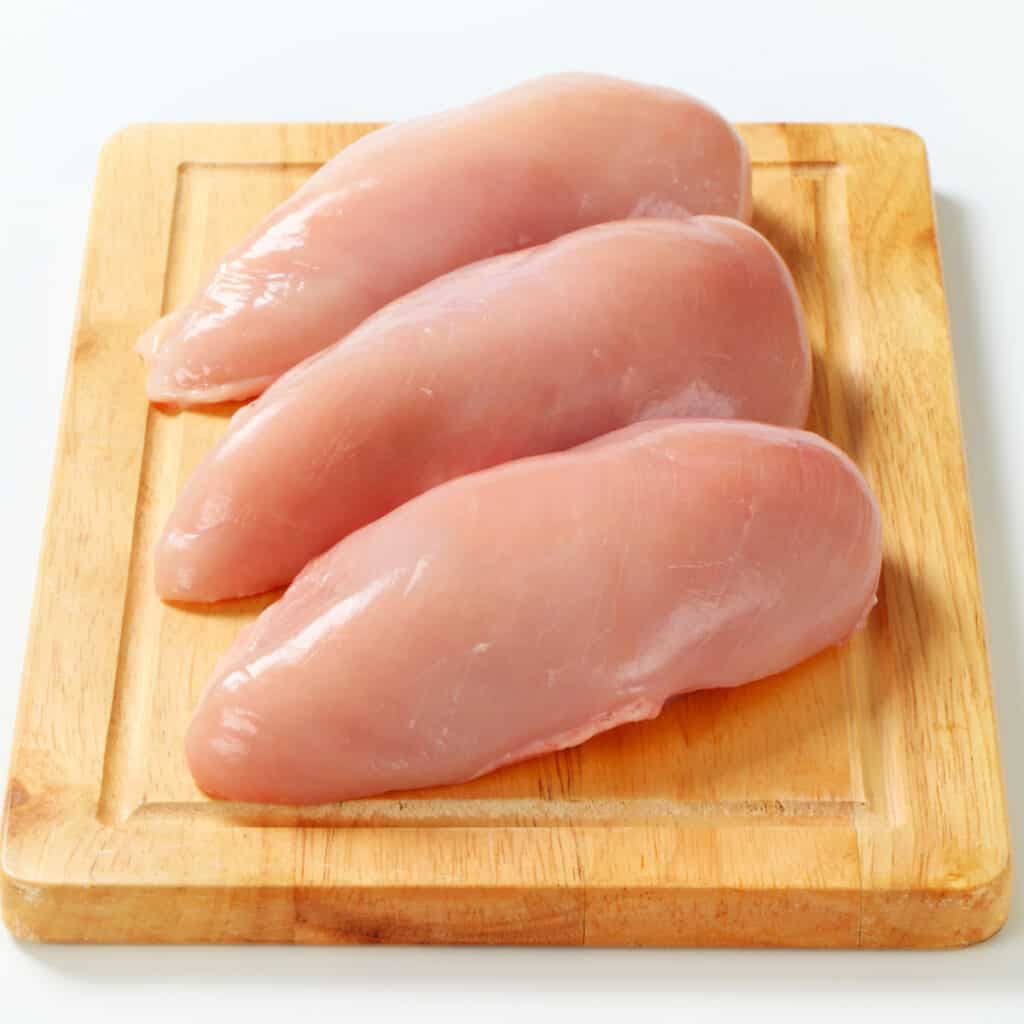 three chicken breasts on a cutting board.