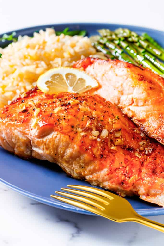 two pieces of garlic butter salmon with roasted asparagus and rice pilaf.