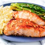 two pieces of garlic butter salmon with roasted asparagus and rice pilaf.