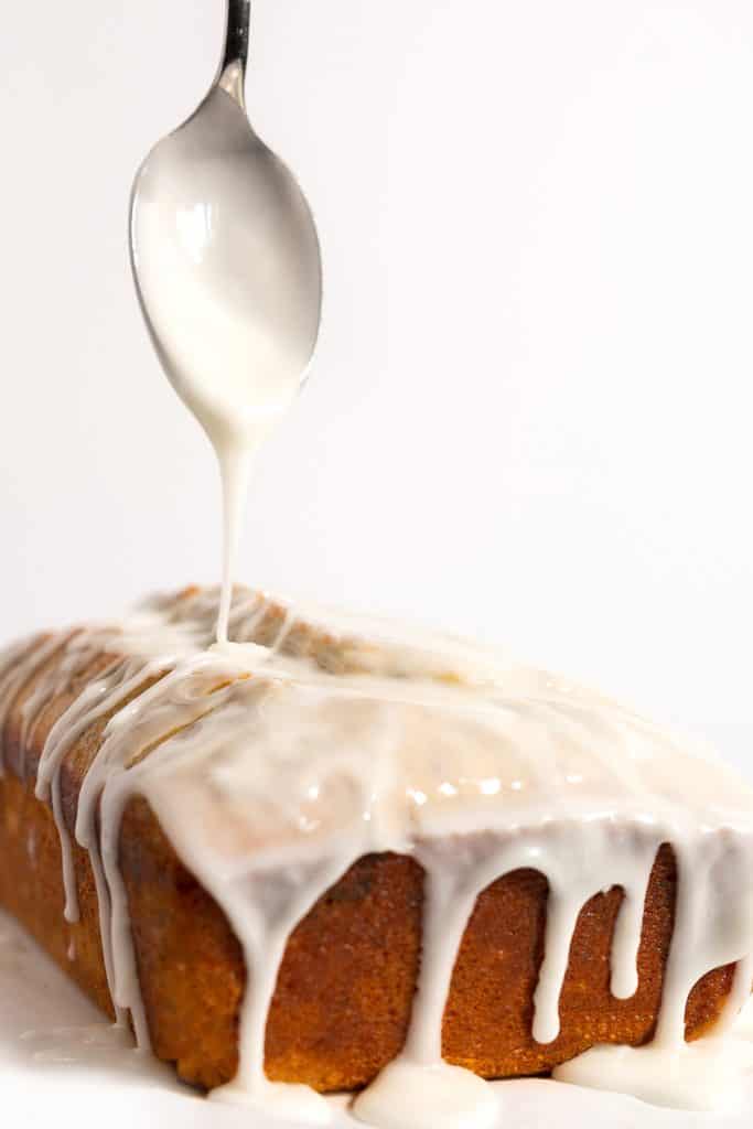 a spoon drizzeling icing onto a pound cake