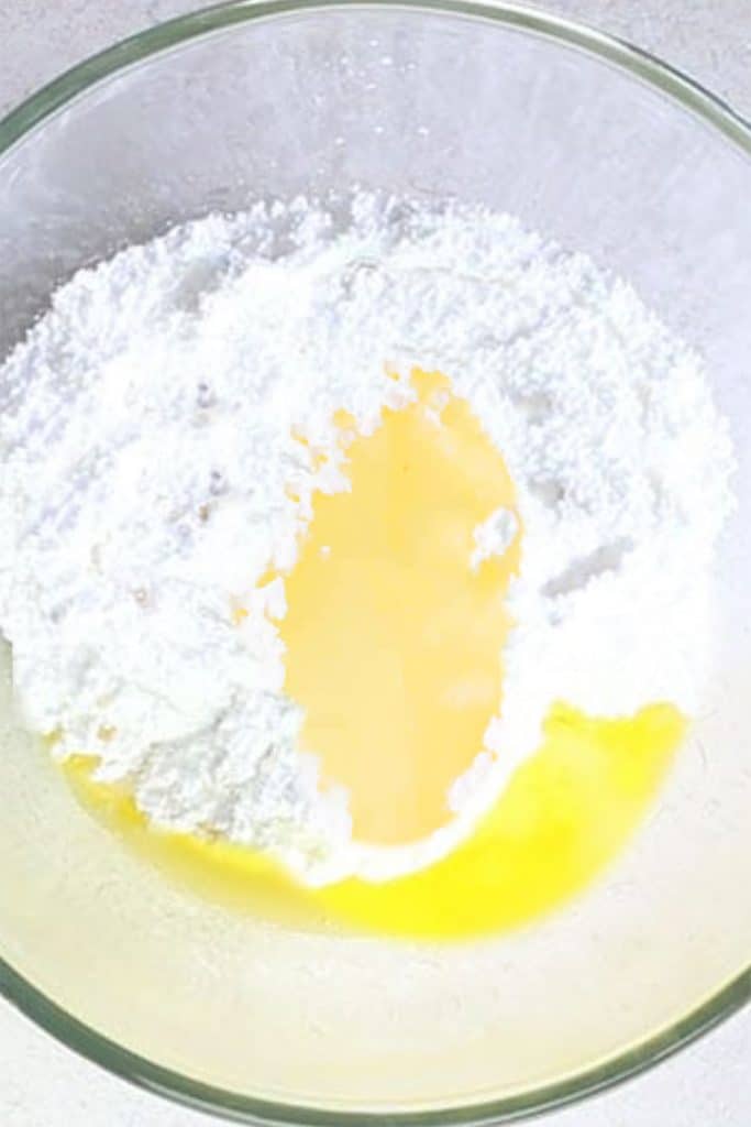 lemon juice added to a bowl with powdered sugar and melted butter