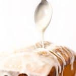 a spoonful of icing being drizzeled onto a pound cake