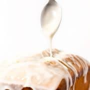 a spoonful of icing being drizzeled onto a pound cake