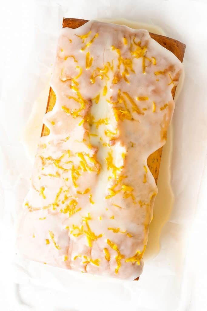 An overhead shot of a lemon loaf cake with icing and lemon zest on top