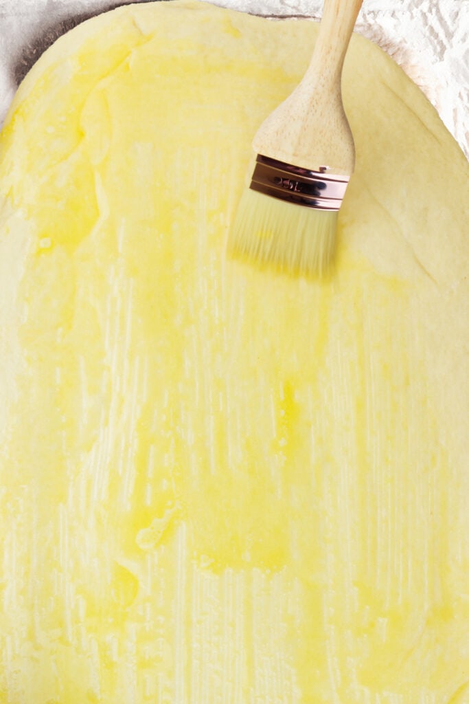 Butter being brushed onto the dough with a pastry brush.