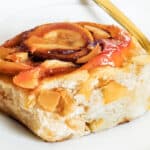 a Cinnamon Roll with Apple Pie Filling on a white plate with a fork.